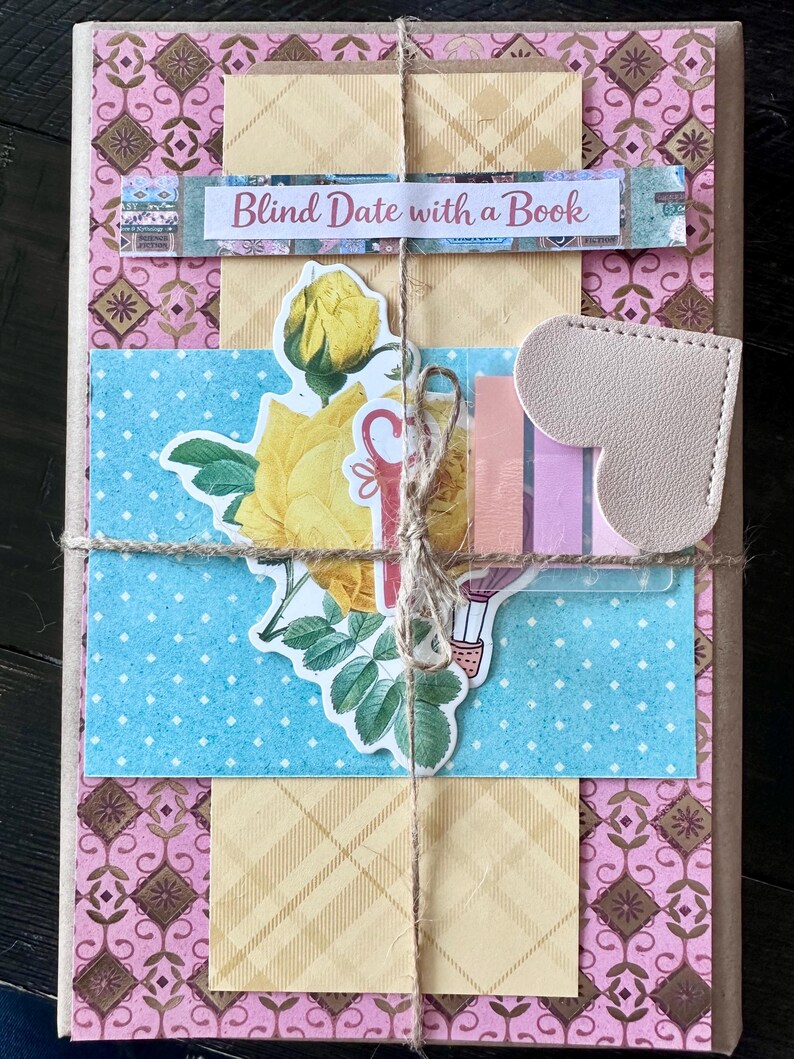 May include: A wrapped book with decorative paper and twine. The cover features a pink and brown floral pattern, with a blue polka dot section and yellow plaid paper. A sticker reads "Blind Date with a Book."