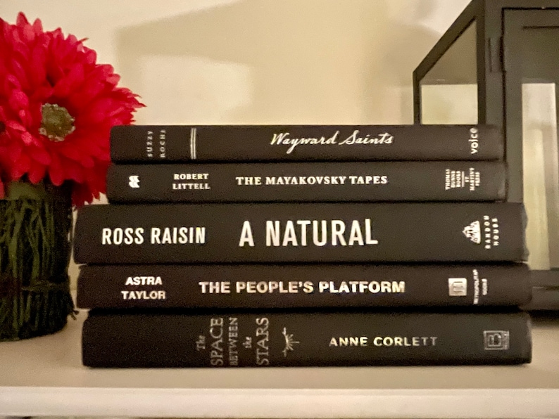 May include: A stack of five black hardback books with white text titles. The titles are "Wayward Saints", "The Mayakovsky Tapes", "A Natural", "The People's Platform", and "The Space Between the Stars".