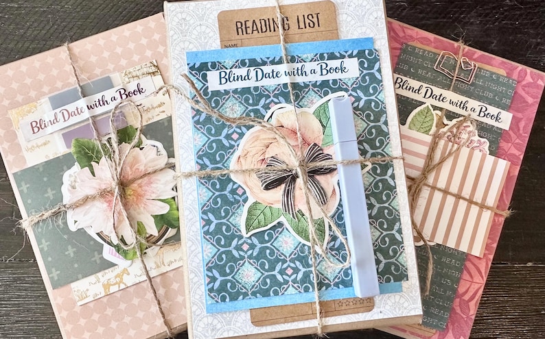 May include: Three wrapped books labeled "Blind Date with a Book" are tied with twine. Each book features decorative paper, floral accents, and a label. One book has a "Reading List" tag. A light blue marker is included.