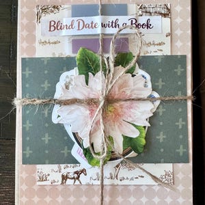 May include: A wrapped book with a decorative flower and twine. The book is wrapped in patterned paper with the text "Blind Date with a Book" on a label. A sticker of a horse is visible.