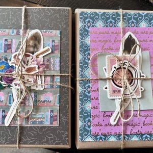 May include: Two wrapped packages tied with twine. One has a gray cover with a floral design and a sticker of a bookshelf, flowers, and a feather. The other has a patterned cover with text and a sticker of a clock and feather.