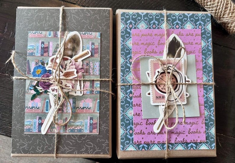 May include: Two wrapped packages tied with twine. One has a gray cover with a floral design and a sticker of a bookshelf, flowers, and a feather. The other has a patterned cover with text and a sticker of a clock and feather.