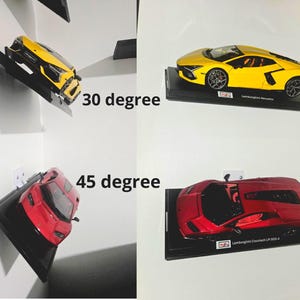 Op de afbeelding: Miniatuur gele en rode Lamborghini modelauto's op zwarte standaards. De gele auto is voorzien van het label "Lamborghini Revuelto" en de rode auto van "Lamborghini Countach LP 800-4". De auto's zijn onder hoeken van 30 en 45 graden gemonteerd.