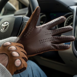 Puede incluir: Un par de guantes de conducir de cuero marr&oacute;n con detalles perforados. Un guante se muestra con los dedos extendidos, mientras que el otro guante est&aacute; parcialmente en la mano de una persona.