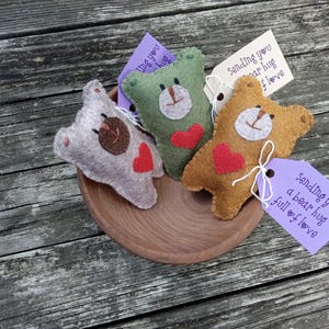 May include: Three felt bear plushies with red hearts, each with a tag that says "Sending you a bear hug full of love".