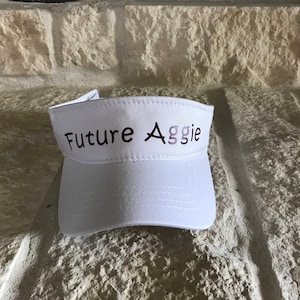 May include: White visor with the text "Future Aggie" in brown lettering.