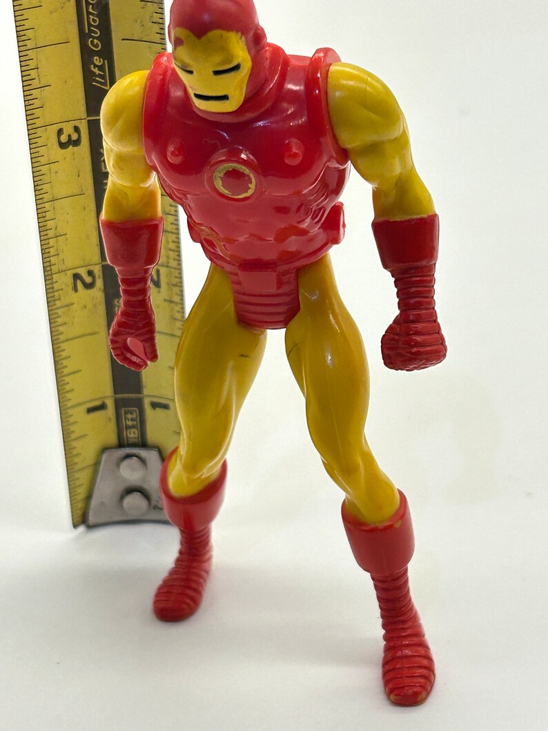 May include: A red and yellow plastic action figure of Iron Man. The figure is approximately 5 inches tall and has a detailed sculpt.
