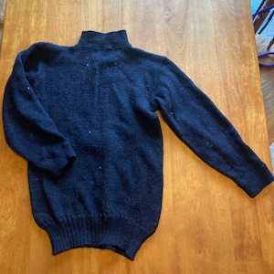 May include: A black mock neck sweater with a ribbed knit texture.