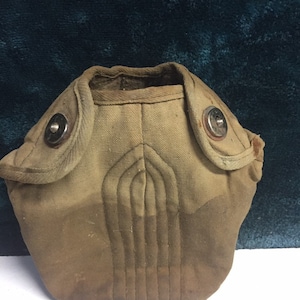 May include: A brown canvas canteen with two metal snaps and a quilted design.