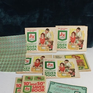May include: A collection of vintage S&H Green Stamps books and an award certificate. The books are green and white with a family on the cover. The books have the text "Quick Saver Book" and "10's and 50's Saver Book". The award certificate is green and white with the text "Award Certificate" and "S&H Green Stamps".
