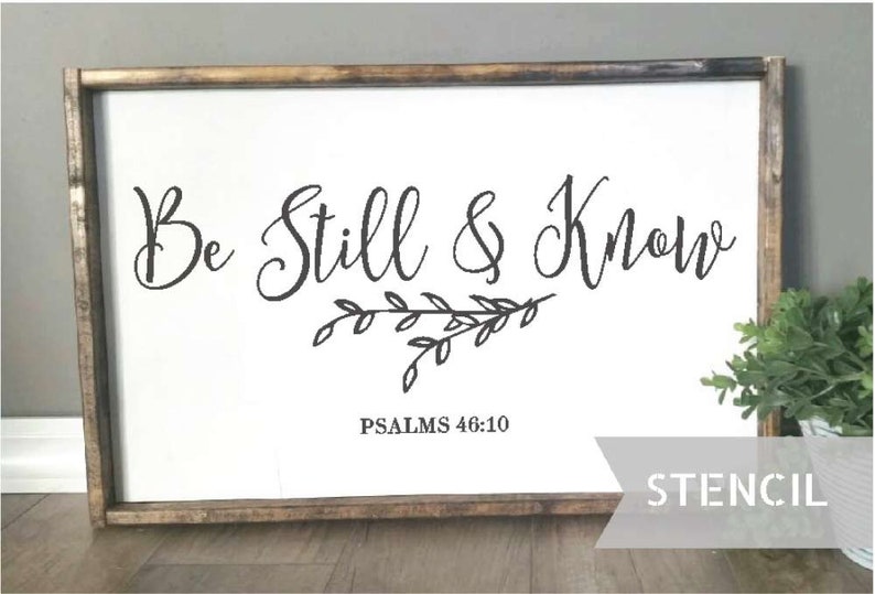 Pu&ograve; includere: Un cartello di legno bianco con il testo "Be Still & Know" in corsivo nero. Sotto il testo c'&egrave; un piccolo ramo con foglie e il testo "PSALMS 46:10". Il cartello &egrave; incorniciato da una cornice in legno marrone e la parola "STENCIL" &egrave; stampata in nero su uno sfondo grigio nell'angolo in basso a destra.