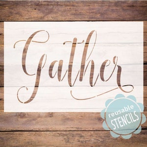 May include: White stencil with the word "Gather" in a cursive font. The stencil is on a wood background and has a blue reusable stencil sticker in the bottom right corner.
