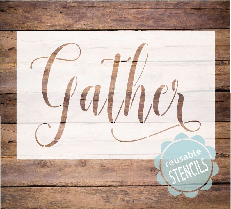 May include: White stencil with the word "Gather" in a cursive font. The stencil is on a wood background and has a blue reusable stencil sticker in the bottom right corner.