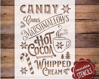 May include: A white stencil with the words "Candy, Canes, Marshmallows, Hot Cocoa, Whipped Cream" and snowflake and tree designs. A candy cane and a mug of hot cocoa are also featured. The stencil is labeled "reusable STENCILS".