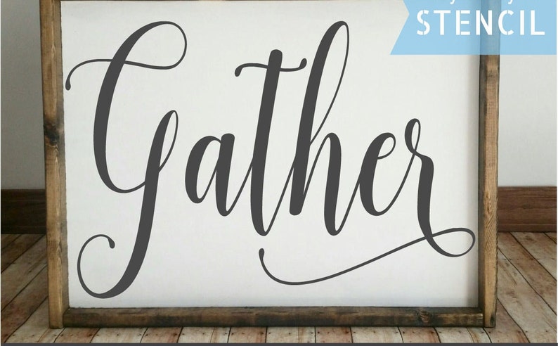 May include: A white wooden sign with the word "Gather" written in black cursive script. The sign is framed with a dark brown wood frame. The word "STENCIL" is written in blue on a white background in the upper right corner of the image.