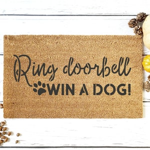 May include: A brown doormat with the text "Ring doorbell win a dog!" in black lettering. A paw print is next to the word "win".