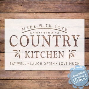 May include: White stencil with the text "MADE WITH LOVE ALWAYS FRESH COUNTRY KITCHEN EAT WELL LAUGH OFTEN LOVE MUCH" in brown lettering. The stencil is on a wood background and has a blue reusable stencil sticker in the bottom right corner.