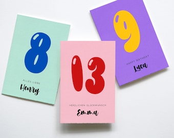 May include: Three rectangular greeting cards featuring large, bubble-style numbers. A mint card with a blue number 8 and the name Henry, a pink card with a red number 13 and the name Emma, and a purple card with a yellow number 9 and the name Luca.