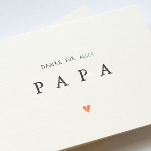 May include: A white card with the text "DANKE F&Uuml;R ALLES PAPA" in black lettering and a small orange heart.