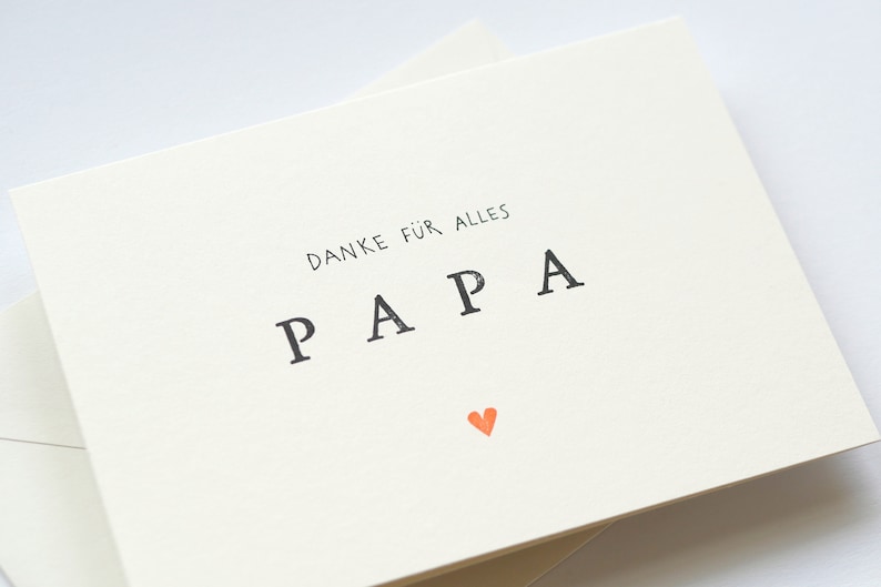 May include: A white card with the text "DANKE F&Uuml;R ALLES PAPA" in black lettering and a small orange heart.