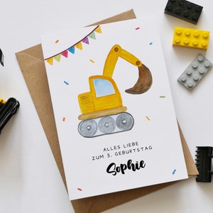 Op de afbeelding: Een gele bouwvoertuig-verjaardagskaart met een aquarel-illustratie van een graafmachine. De kaart heeft een kleurrijk lint en confetti. De tekst op de kaart luidt "Alles Liebe zum 3. Geburtstag Sophie".