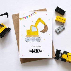 Op de afbeelding: Een witte kaart met een gele en zwarte speelgoedgraafmachine met een bruine schep. De kaart is versierd met kleurrijk confetti en de tekst "Alles Liebe Matteo".