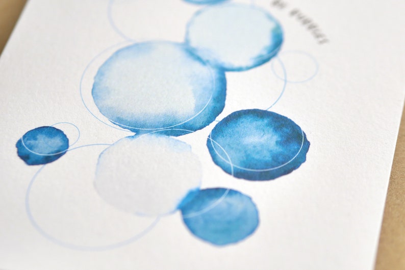 May include: Watercolor art print featuring blue circles of varying sizes and shades, connected by thin, light blue lines. The design is on a white background, with a few words in the upper right corner.