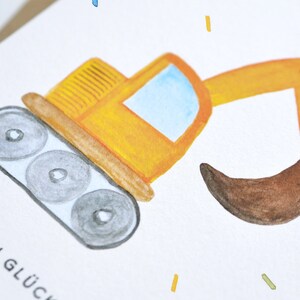 Op de afbeelding: Een gele speelgoedgraafmachine met een bruine schep, op een witte achtergrond met de tekst "Herzlichen Gl&uuml;ckwunsch" in zwart.
