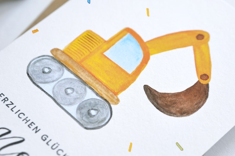 Op de afbeelding: Een gele speelgoedgraafmachine met een bruine schep, op een witte achtergrond met de tekst "Herzlichen Gl&uuml;ckwunsch" in zwart.