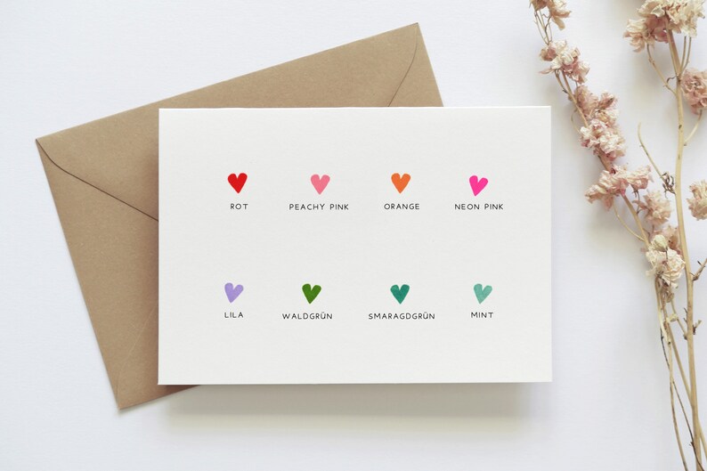 Op de afbeelding: Een witte kaart met een kleurenkaart met kleine hartjes in verschillende kleuren. De kleuren zijn in het Duits gelabeld: Rot, Peachy Pink, Orange, Neon Pink, Lila, Waldgr&uuml;n, Smaragdgr&uuml;n en Mint.