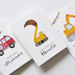 Op de afbeelding: Drie verjaardagskaarten met illustraties van bouwvoertuigen. De eerste kaart heeft een rode brandweerwagen met een ladder, de tweede kaart heeft een gele graafmachine en de derde kaart heeft een gele bulldozer. De kaarten zijn gepersonaliseerd met de namen Alexander, Moritz en Neo.