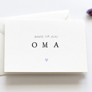 Op de afbeelding: Een witte kaart met de tekst "Danke f&uuml;r alles" en "OMA" in zwarte letters. Een klein paars hartje bevindt zich onder de tekst.