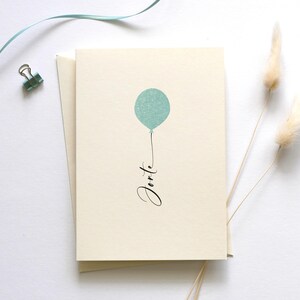 May include: A blank card with a light blue balloon and the word "Forte" written in black calligraphy.
