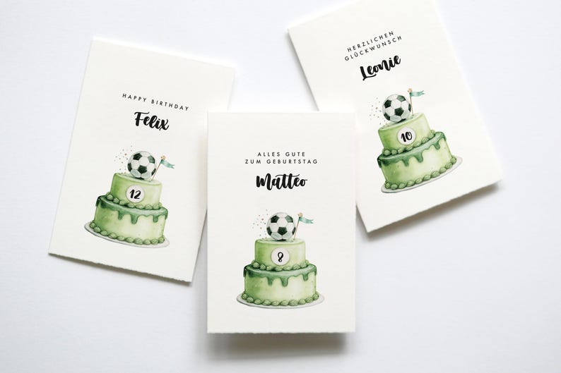 May include: Three birthday cards with watercolor illustrations. Each card features a two-tiered green cake topped with a soccer ball. The cards have names and ages written on them, with text such as "Happy Birthday" and "Alles Gute zum Geburtstag".