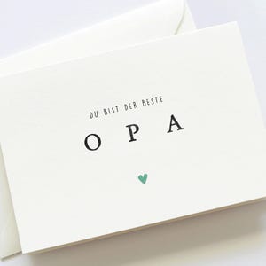 Op de afbeelding: Een witte kaart met de tekst "Du bist der beste Opa" en een klein groen hartje.