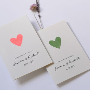 May include: Two wedding cards with a pink and green heart on each. The cards say "Alles Liebe zur Hochzeit" and "Jasmin & Robert" with the date "06-07-2024".