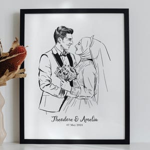 以下が含まれることがあります： 結婚式の衣装を着たカップルの白黒の線画イラストが描かれた黒い額縁入りのプリント。人物の下にはTheodore & Ameliaと07 May 2024の文字が印刷されており、ドライフラワーが入ったベージュの花瓶の隣に飾られています。