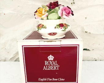 Könnte beinhalten: Eine Schale aus Royal Albert English Fine Bone China mit einem Blumenmuster aus gelben, rosafarbenen und dunkelroten Rosen. Die Schale steht auf ihrer originalen weiß-kastanienbraunen Schachtel, die das Royal Albert Kronenlogo zeigt.