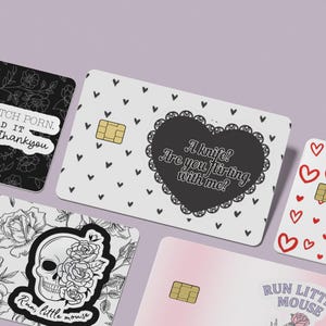 Puede incluir: Un conjunto de tarjetas de cr&eacute;dito decorativas con varios dise&ntilde;os. Una tarjeta presenta un patr&oacute;n floral con el texto "I don't watch porn. I read it like a lady, thankyou." Otra tarjeta tiene una calavera con rosas y el texto "Run little mouse."