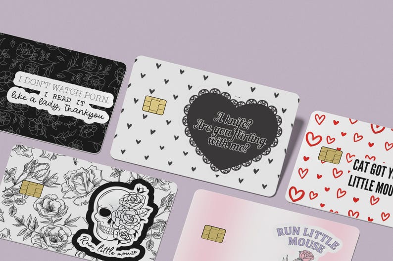 Puede incluir: Un conjunto de tarjetas de cr&eacute;dito decorativas con varios dise&ntilde;os. Una tarjeta presenta un patr&oacute;n floral con el texto "I don't watch porn. I read it like a lady, thankyou." Otra tarjeta tiene una calavera con rosas y el texto "Run little mouse."
