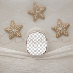 May include: A neutral-toned baby bonnet with a cut-out face area, set against a soft, textured backdrop. Three star-shaped cookies with white icing are arranged around the bonnet, creating a festive, seasonal theme.