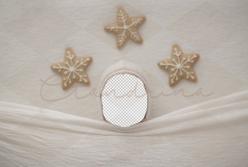 May include: A neutral-toned baby bonnet with a cut-out face area, set against a soft, textured backdrop. Three star-shaped cookies with white icing are arranged around the bonnet, creating a festive, seasonal theme.