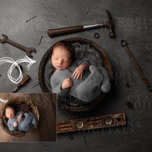 Op de afbeelding: Een pasgeboren babyjongen slaapt in een houten kom omringd door gereedschap, waaronder een hamer, een moersleutel en spijkers. De baby draagt een grijze gebreide outfit.