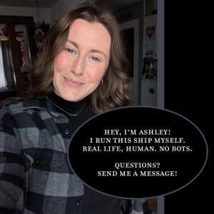 K&ouml;nnte beinhalten: Eine Frau mit schwarzem Rollkragenpullover und einem schwarz-grau karierten Hemd l&auml;chelt. Eine schwarze ovale Sprechblase enth&auml;lt den Text: "HEY, I'M ASHLEY! I RUN THIS SHIP MYSELF. REAL LIFE, HUMAN. NO BOTS. QUESTIONS? SEND ME A MESSAGE!"