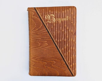 May include: A brown leather-bound journal with a gold embossed design and the text "2B Bryant" on the front cover.