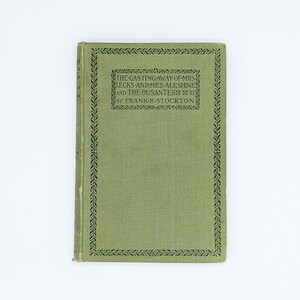 May include: A green book with a black border and text that reads "THE CASTING AWAY-OF-MRS LECKS-AND-MRS-ALESHINE AND THE DUSANTES*** BY FRANK-R-STOCKTON"