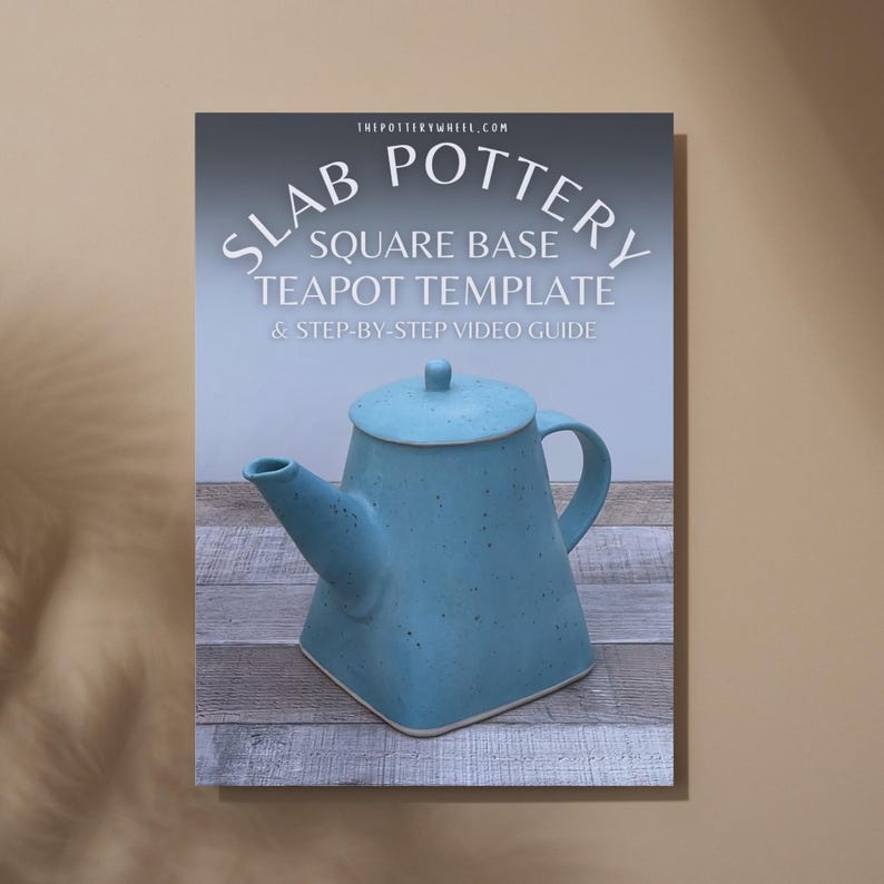 May include: A blue square-based teapot with a matching lid is featured on a poster. The poster includes the text "SLAB POTTERY SQUARE BASE TEAPOT TEMPLATE & STEP-BY-STEP VIDEO GUIDE" and the website address "THEPOTTERYWHEEL.COM". The teapot is displayed on a wooden surface.