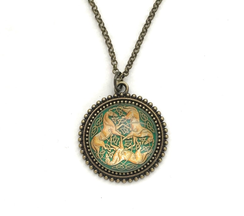 Celtic horse necklace.  3 golden colored horses intertwined with Celtic knots on a green background. Image is placed under a glass cabochon and placed into a brass tray setting with a beaded edge. Chain is 24 inches long.