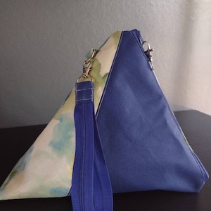 May include: A triangular blue and white fabric bag with a zipper closure and a blue zippered strap.