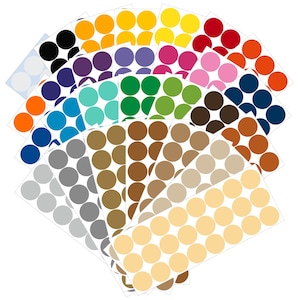 May include: A collection of colorful round stickers in various shades, including black, purple, blue, green, brown, and yellow. The stickers are arranged in a fan shape, with each sheet displaying a different color. The stickers are on a white background.